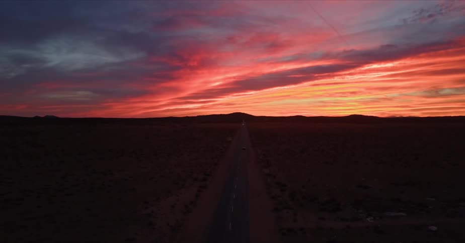 A car travels on a rural road at sunset