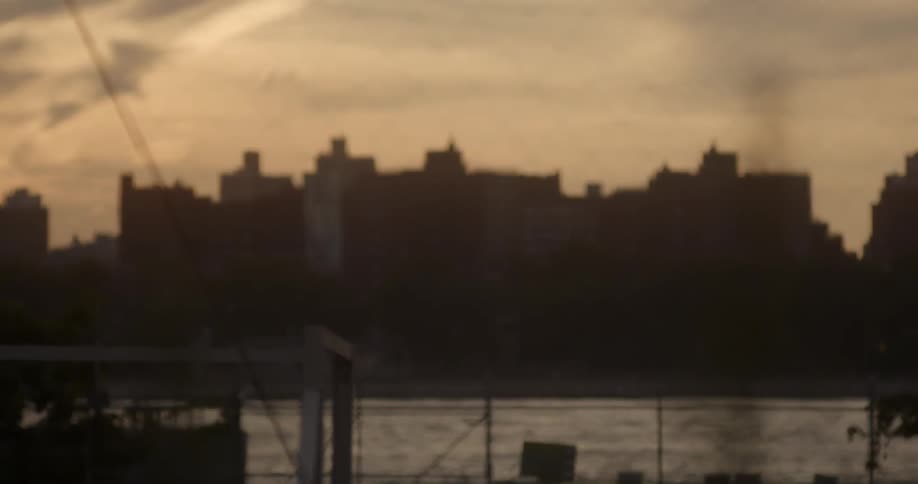 The sun is setting near a fence