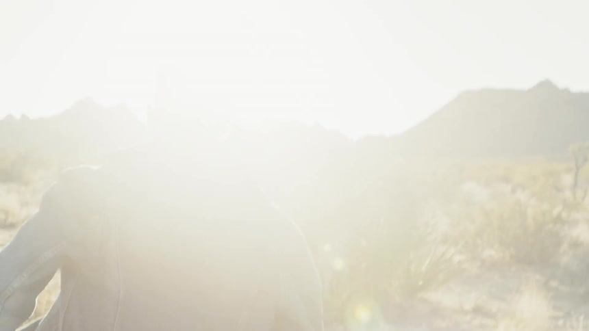 A man is walking in bright sunlight near mountains