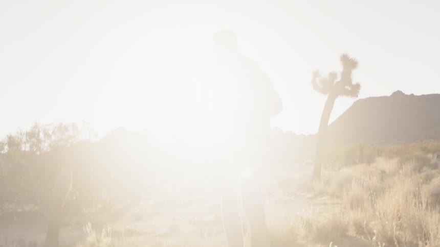 Backside of a man running through a desert towards mountains