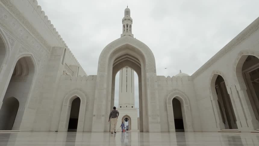 A man enters the inner courtyard of a white marble mosque