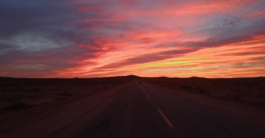 A long road in a desert state under a sunset