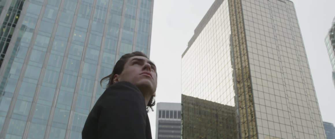 Man turns and looks around him as he stands in a city