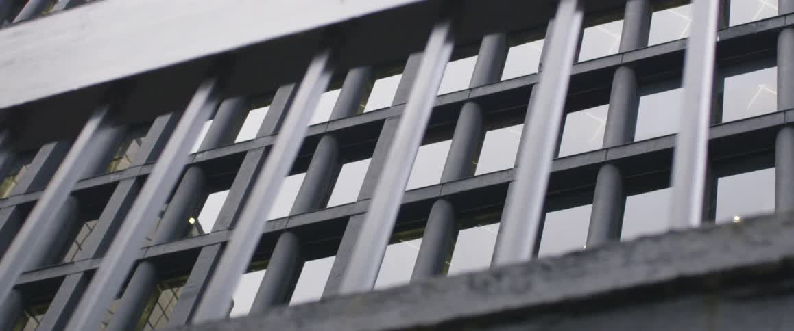 A tall building is viewed through iron bars