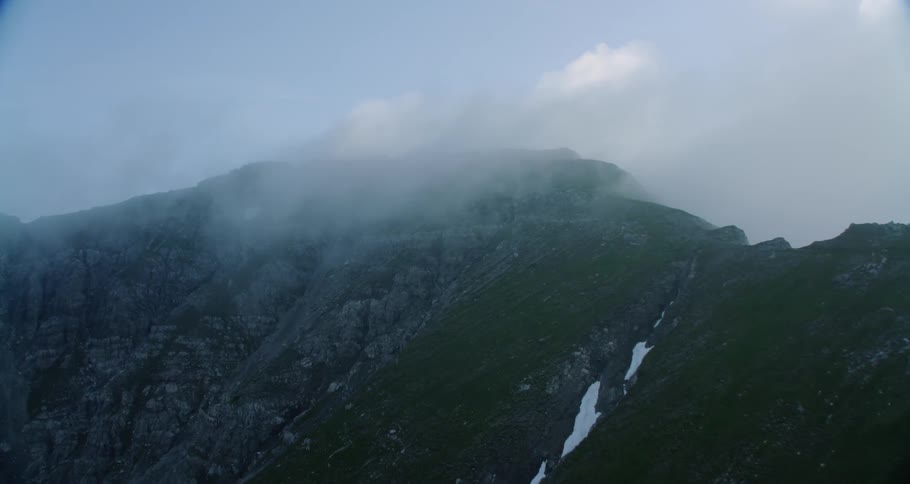 Clouds float over the mountain under a blue sky