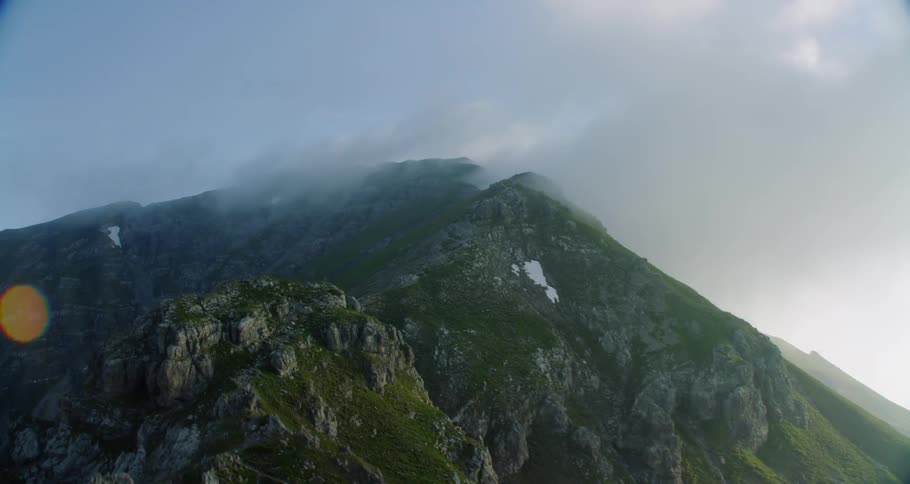 The clouds roll over the green mountain