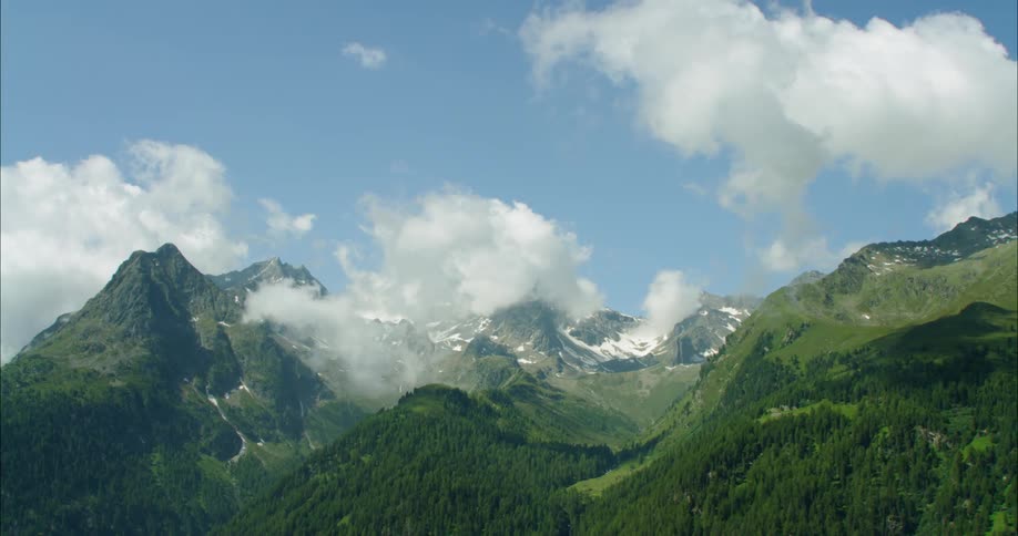 Clouds float above snowy mountains