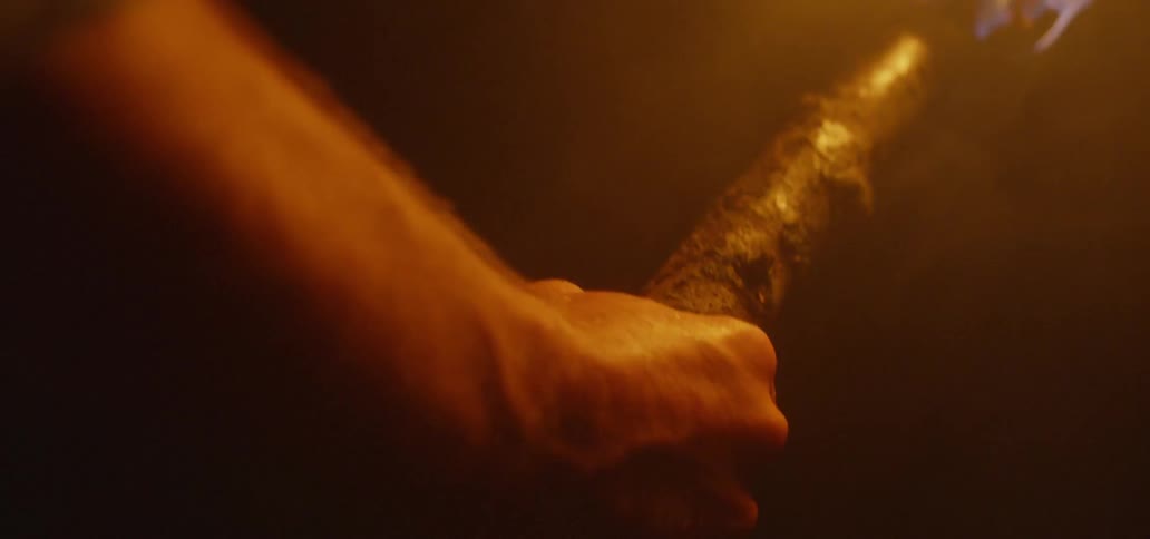 A man carries a flaming torch through the dark