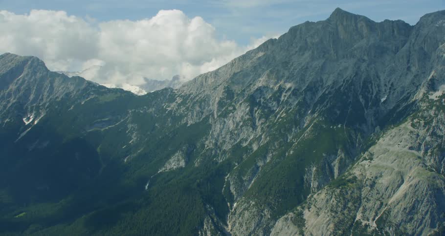 The vast green mountain range has clouds below it