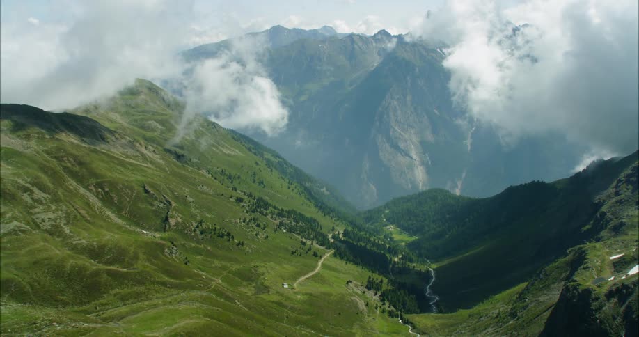 Clouds float over the valley between the mountains
