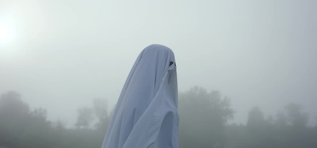 Person wearing a white sheet ghost costume in the fog