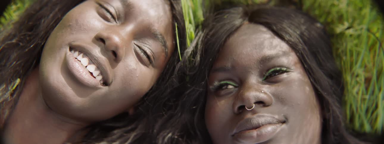 Two woman laying on the grass talking to one another