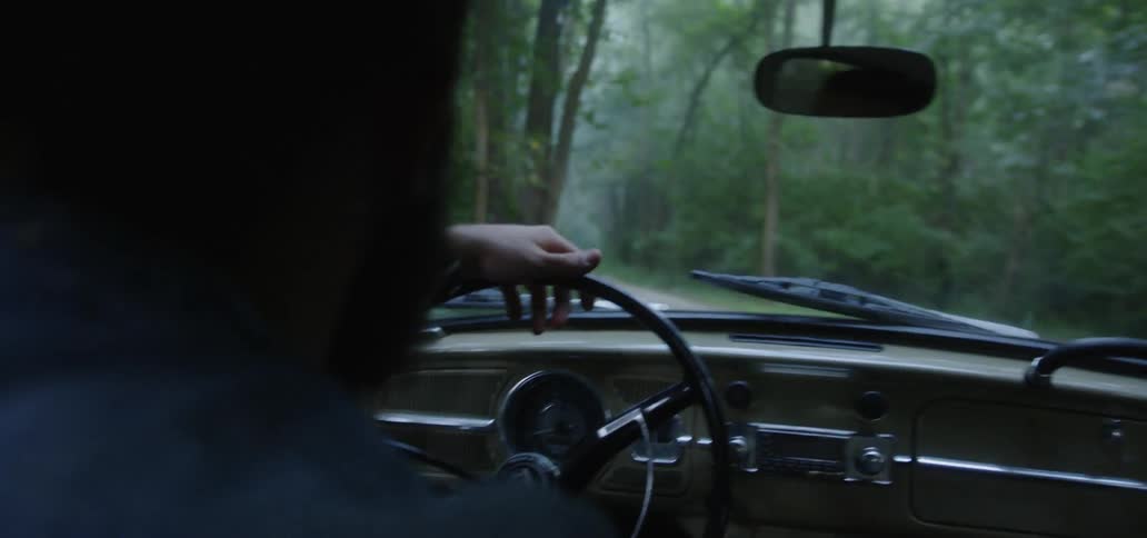 Man rides in old car through forest