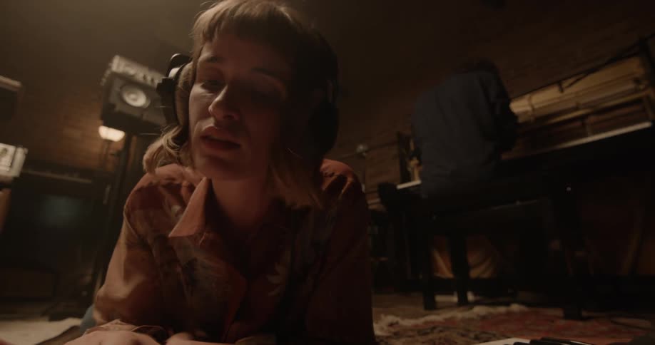 A woman is wearing headphones and laying on the ground