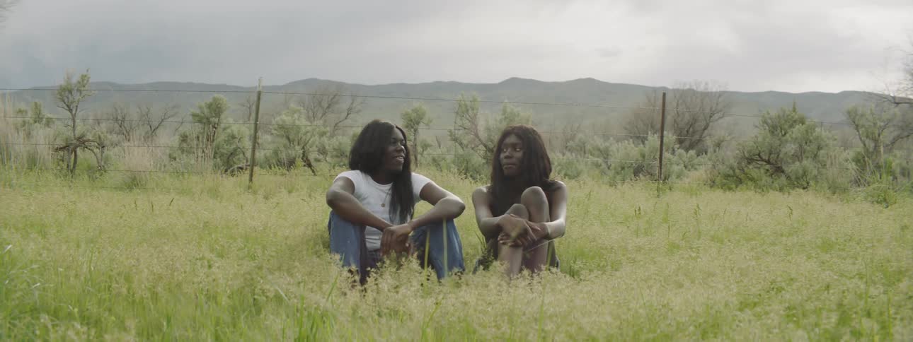 Two women are sitting in the grass outdoors