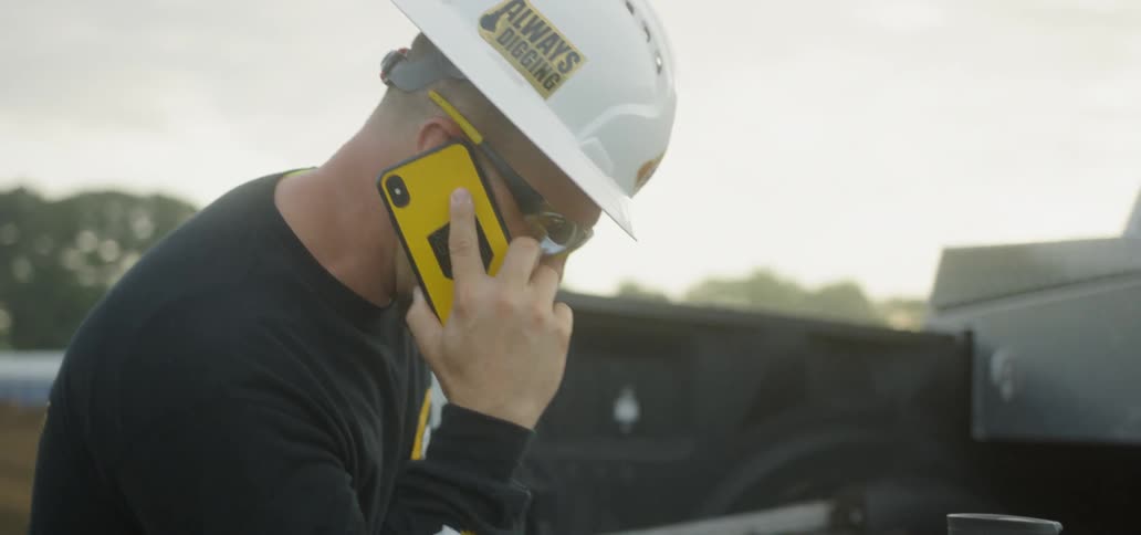 A man in a hard hat talks on a cell phone