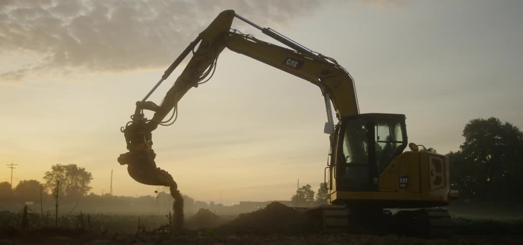 A person is operating a crane and moving dirt