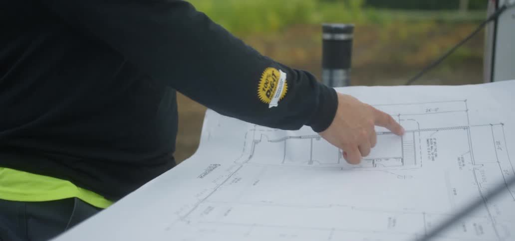 Man Looking Over Blueprints At Construction Site
