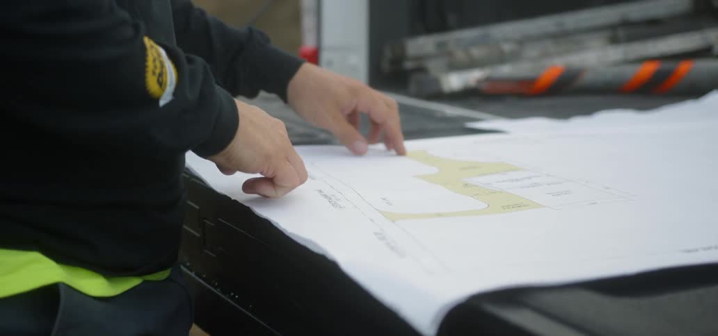 A person running their fingers over a large sheet of paper
