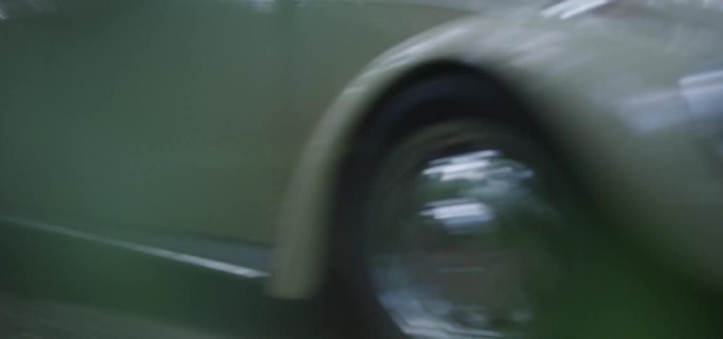 An old volkswagen beetle travels on a forest road