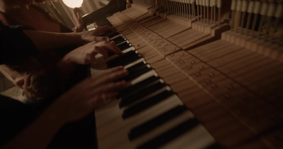 Young man and woman play music on the piano with three hands