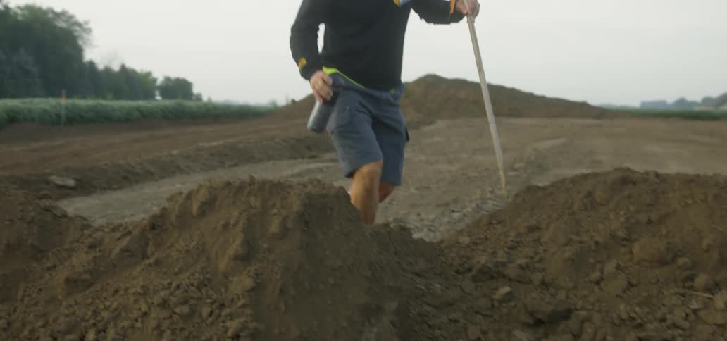 A construction worker walks on freshly dug soil