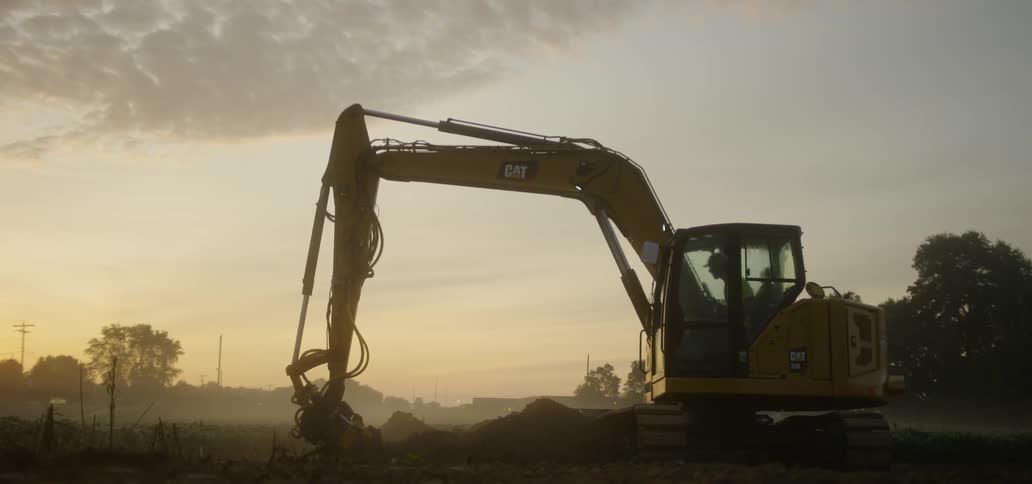Excavation machine digs the soil at sunset