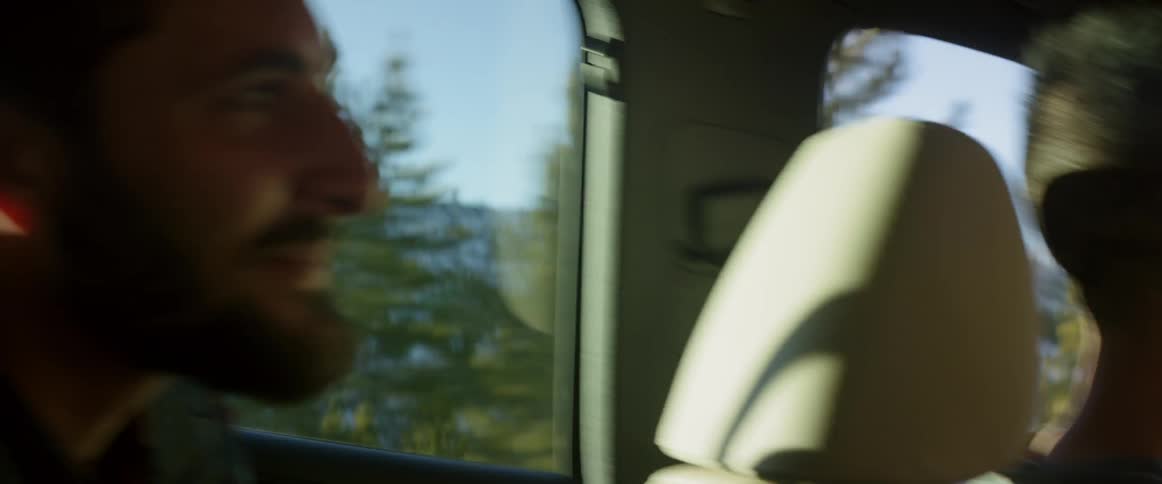 An drives a car with a man talking to him in the back seat