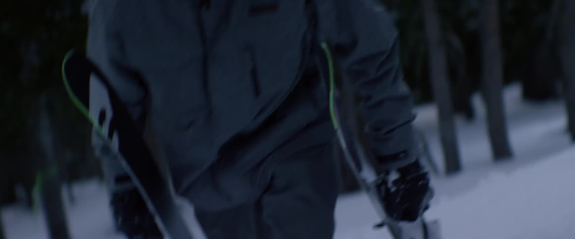 Man walks in the snow holding his skis and poles