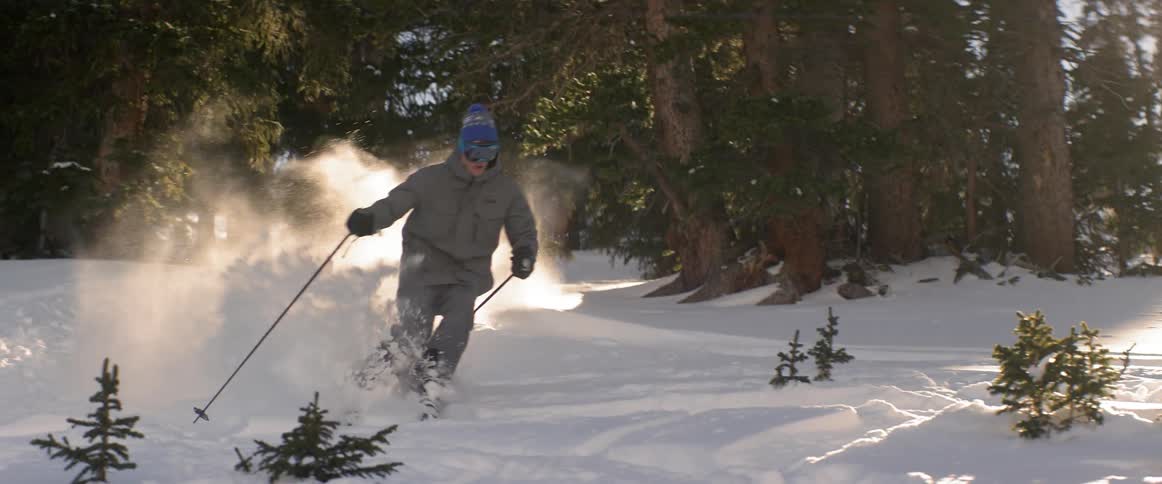 Man skis down a hill surrounded by trees