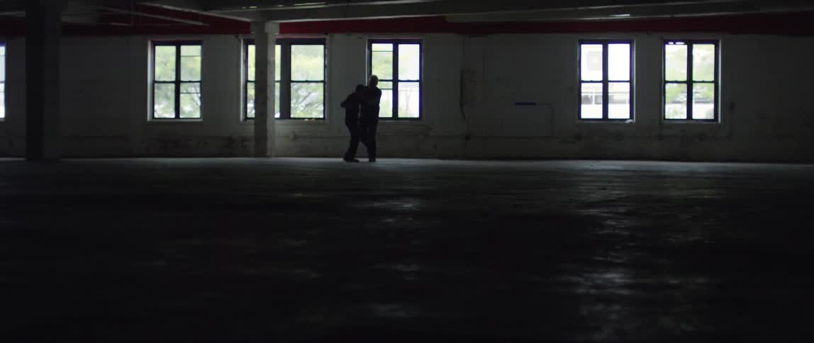 Two men are fighting in slow motion inside an empty building