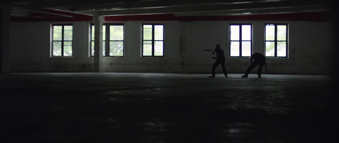 Two men fighting in an empty room