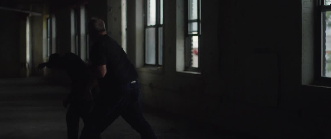 A man in a black shirt punches another man and knocks him down