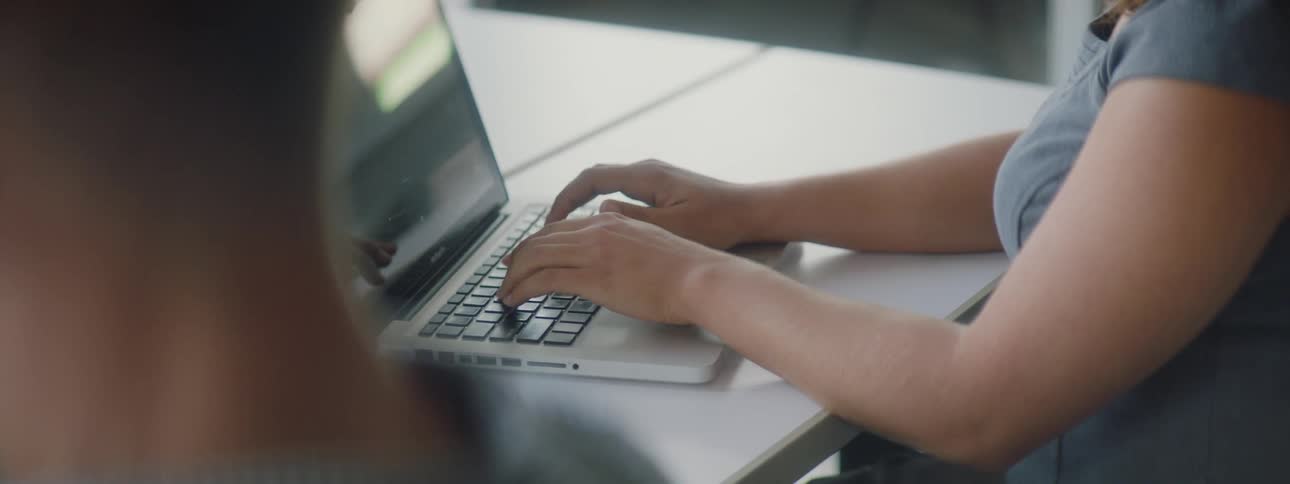A woman is typing at her laptop in the office
