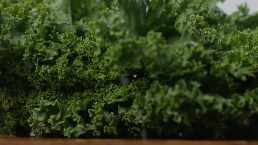 Moist kale leaves drop onto cutting board