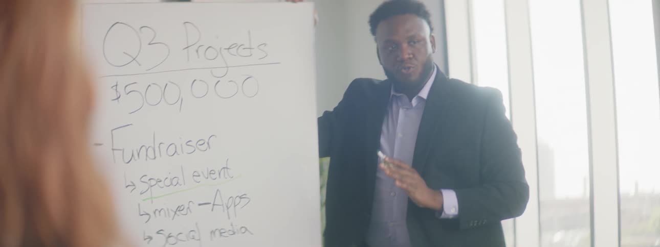 A man underlining text on a whiteboard in an office