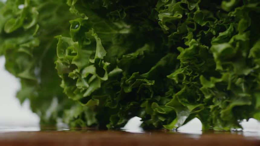 Wet lettuce hits a wooden cutting board