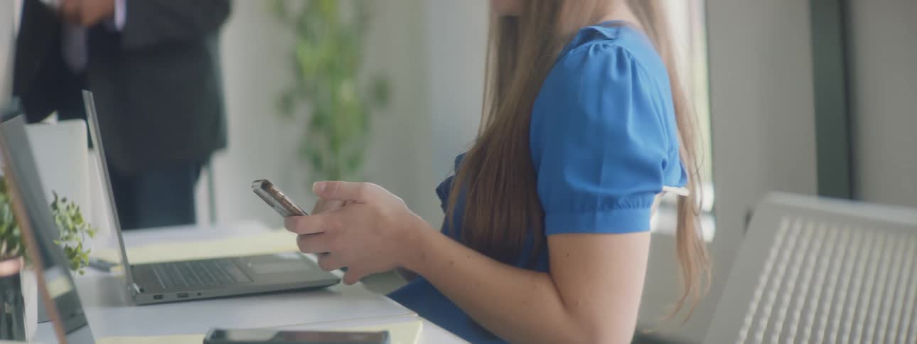 Woman typing on a cell phone while sitting in an office