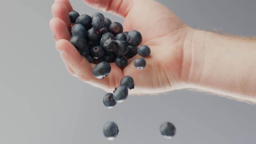 A man drops a handful of blueberries