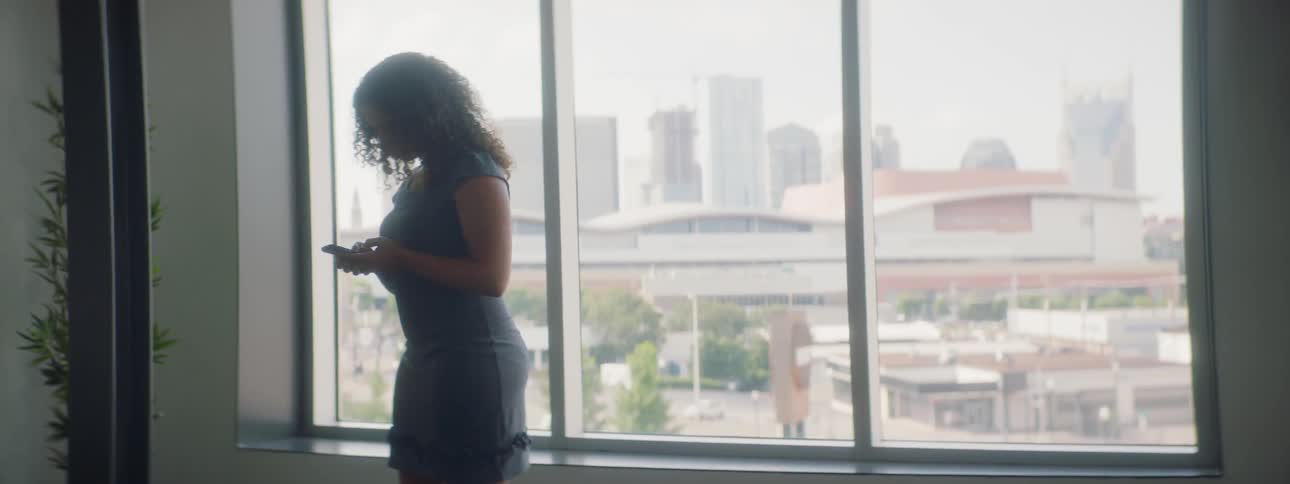 A woman walks past the large window using her phone