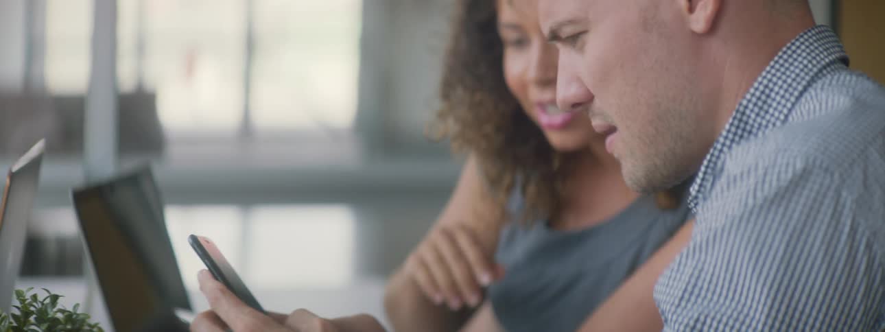 A man uses his phone as he sits by a woman