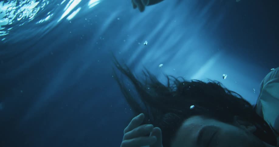 A man sinking underwater with his eyes closed