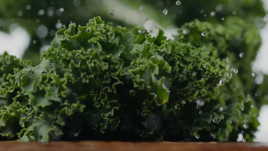 Kale falls onto a wet cutting board