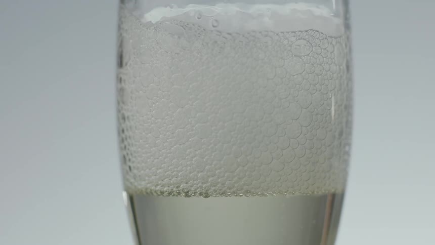 Bubbles pop in a glass of champagne