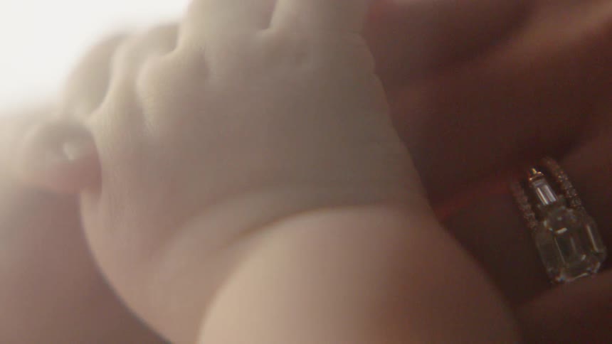 Mother is holding infants hand