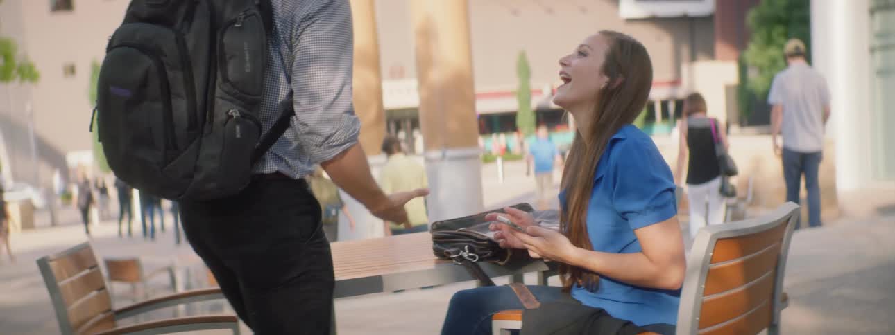 A man walks up to shake hands with a woman and sit