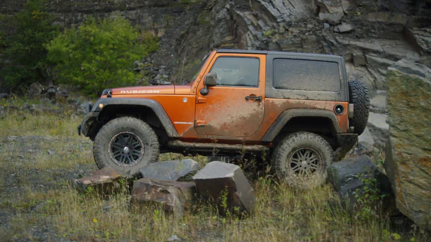 Jeep is driving over large rocks in the wilderness