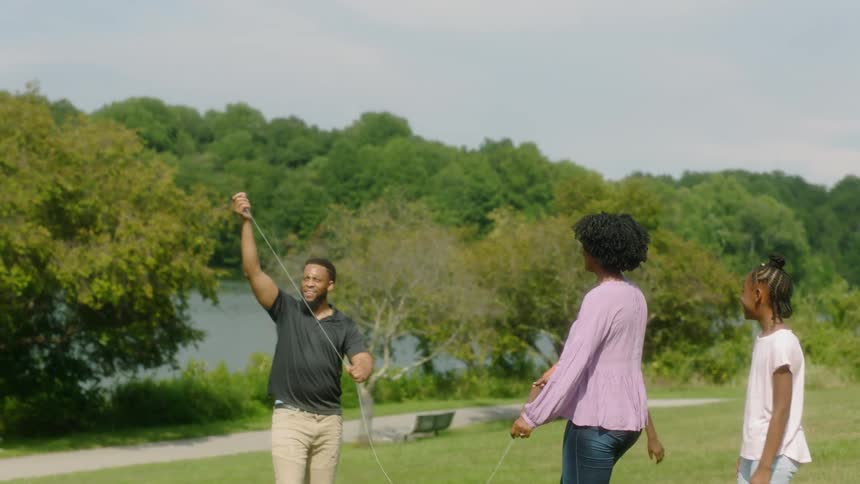 Family is flying kite on sunny day in the park