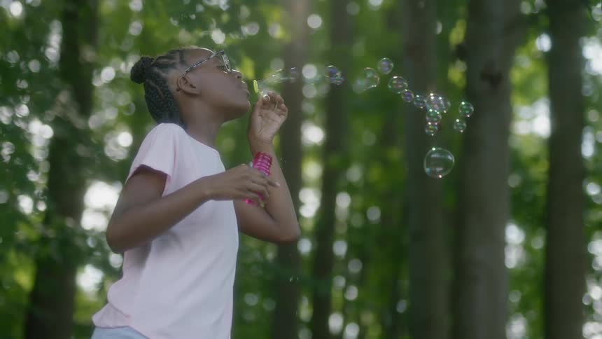 Girl blows bubbles in forest
