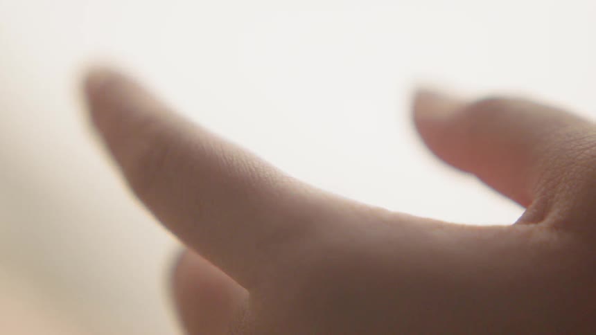 A baby hand holding an adult's finger